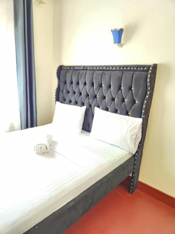 - un lit avec une tête de lit noire et des oreillers blancs dans l'établissement Zuri homes (Mtwapa), à Mtwapa
