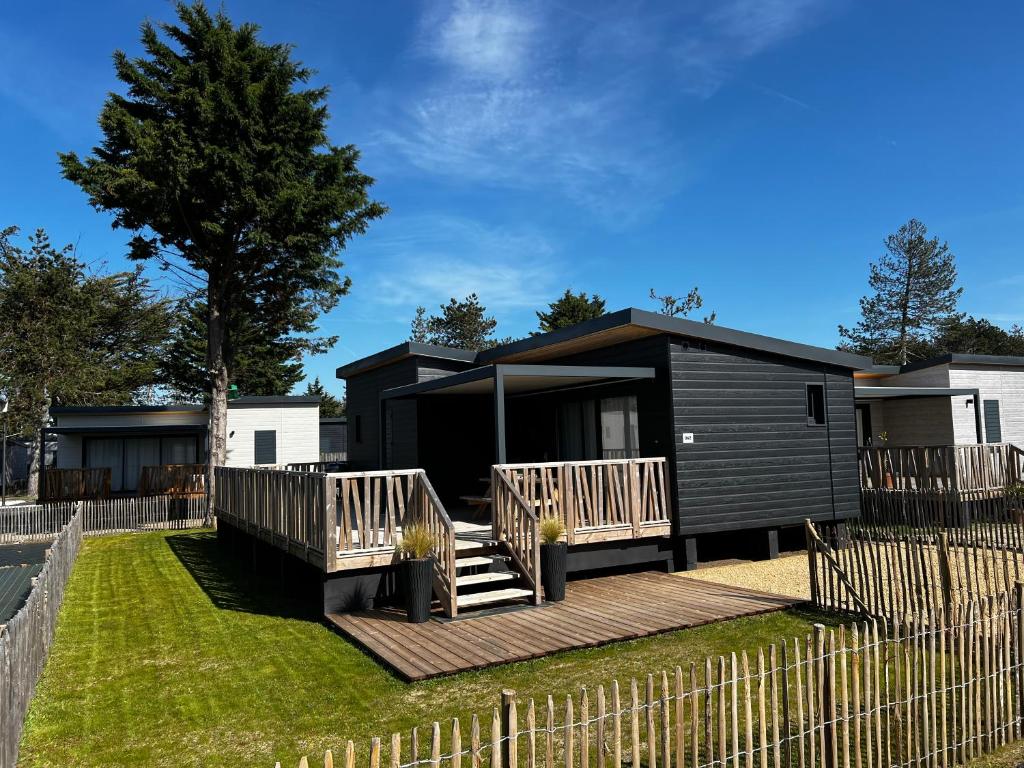 a black tiny house with a wooden deck at Le Chalet d'Angel in Jullouville-les-Pins