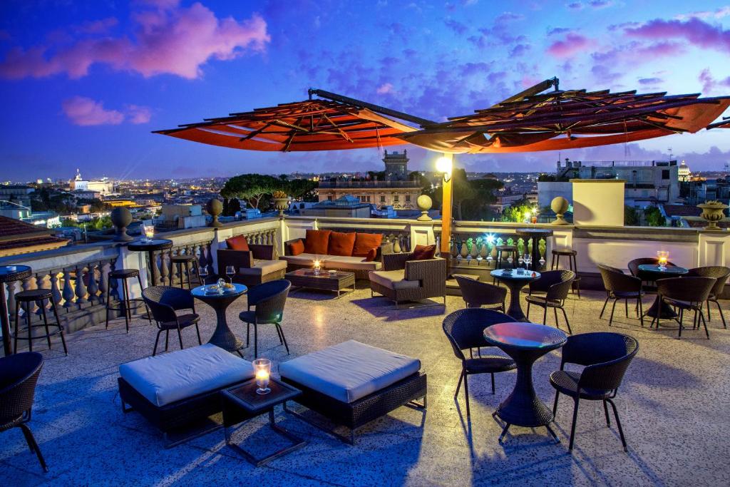 a rooftop patio with tables and chairs and a couch at Hotel Savoy in Rome