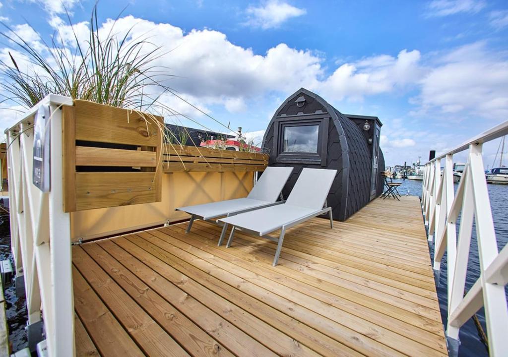 a deck with a white bench and a black tent at Boathouses - Overnat på vandet ved Limfjorden in Vinderup