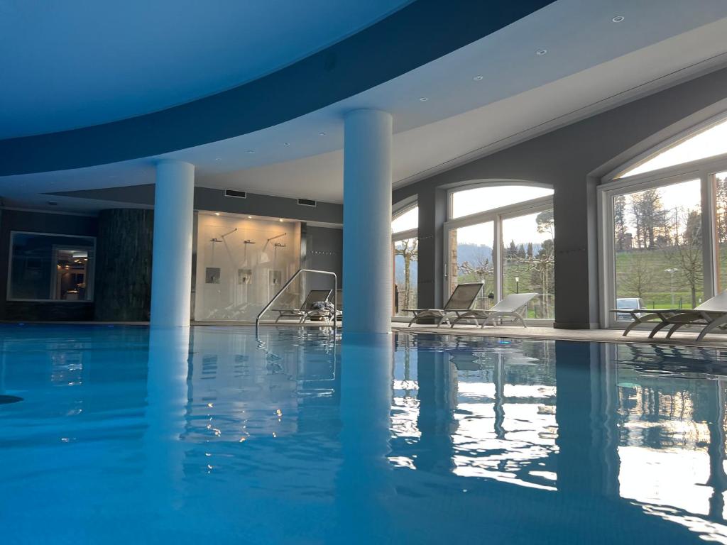 a swimming pool with chairs in a building at Bes Hotel Terme di Palazzago in Palazzago
