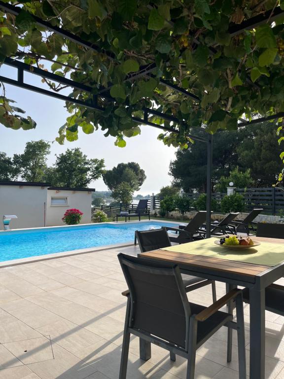 una mesa y sillas junto a una piscina en Stancia Rosa - apartment Kiwi en Poreč