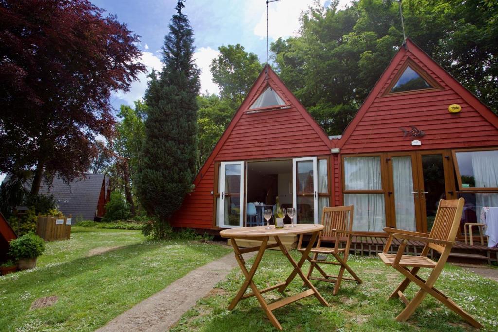 a red house with a table and chairs in the yard at Chalet Fiftynine in Deal