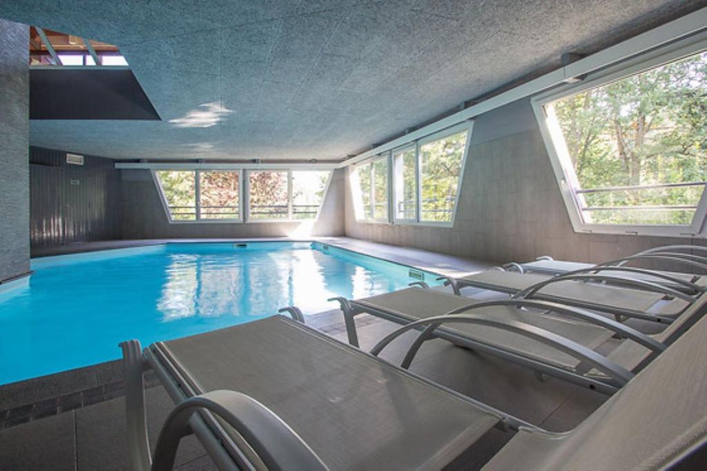 uma piscina com um monte de cadeiras em Hôtel Restaurant La Vallée Noble em Soultzmatt