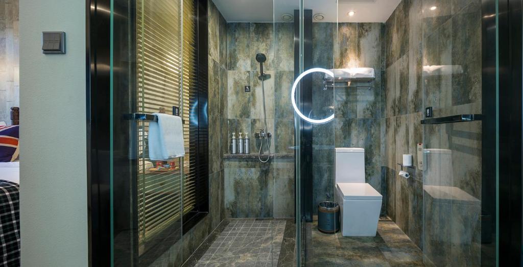 a bathroom with a glass shower and a toilet at Mehood Theater Hotel, Changzhou Dinosaur Park in Changzhou