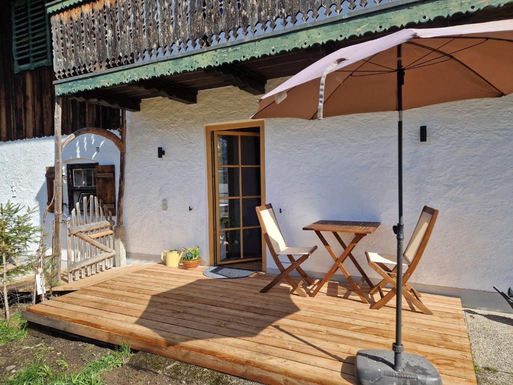 a wooden deck with two chairs and an umbrella at Sonnseitn FW in Bad Heilbrunn