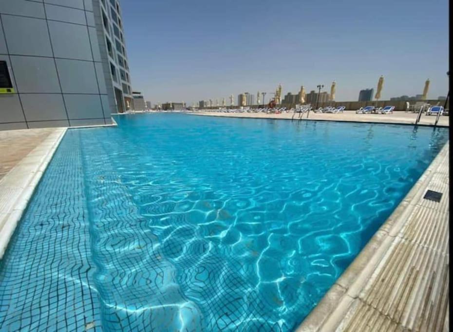 a swimming pool with blue water in a building at Luxury Home Corniche Tower 2 BHK pool gym wifi 20min Dubaï in Ajman 