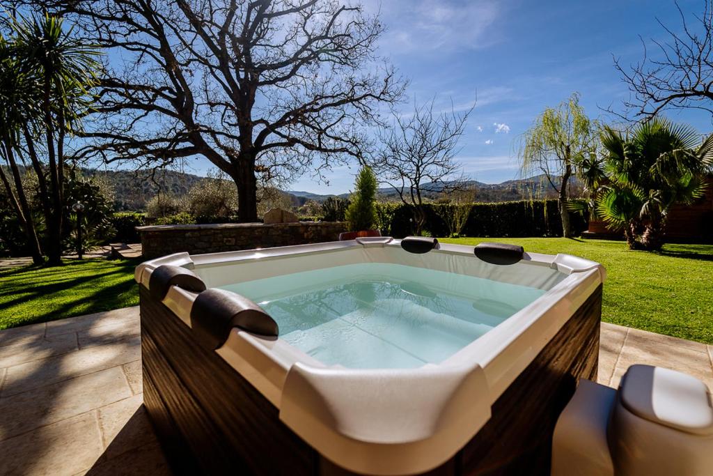 una gran bañera de hidromasaje en un patio trasero con un patio en Villa La Quercia - Garden&Relax en Gavorrano