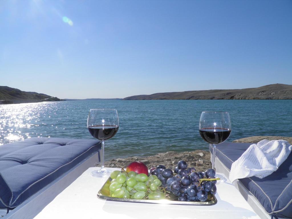 a table with two glasses of wine and a tray of fruit at Apartments Perla in Dinjiška