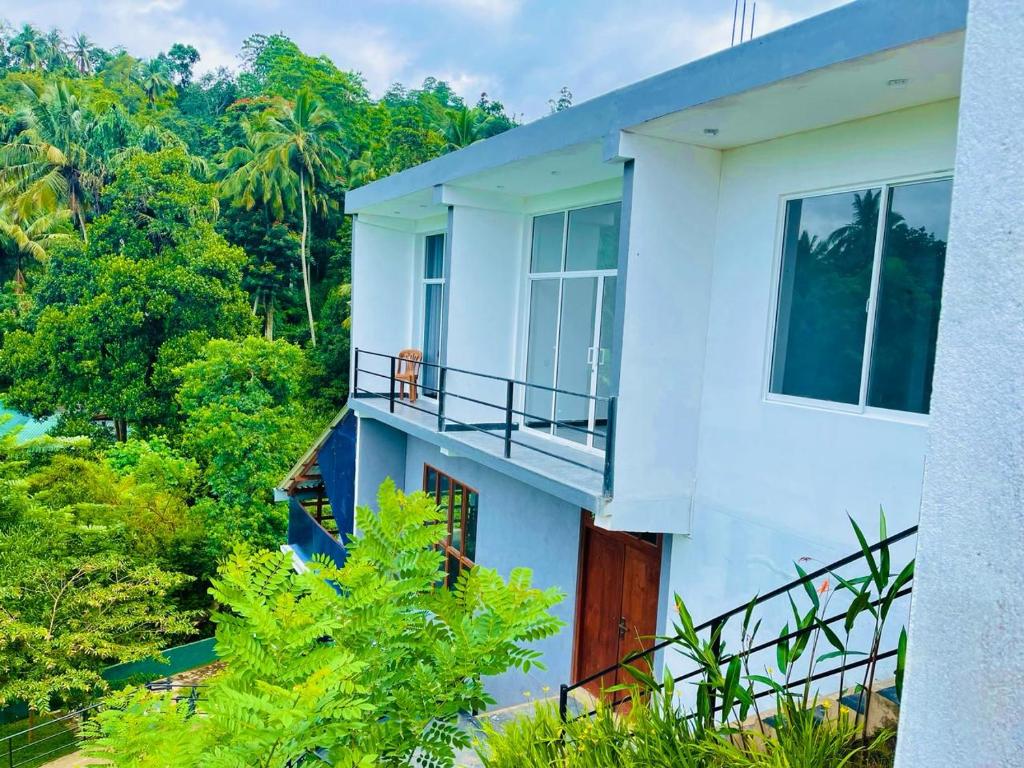 a white house with a balcony and trees at Hanthana SK Paradise in Gampola