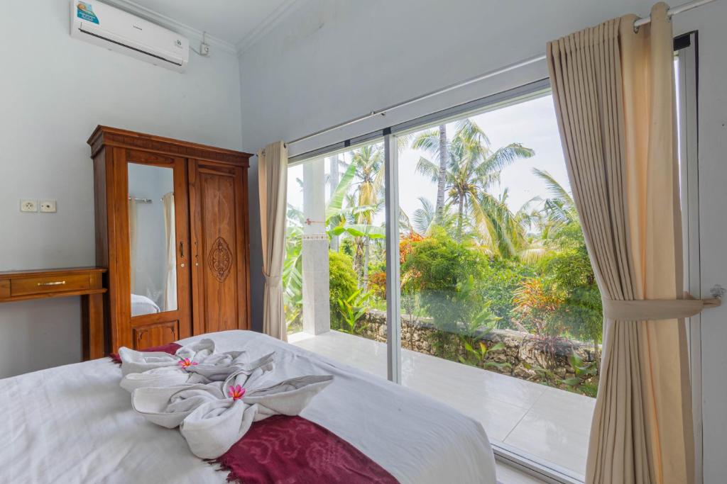 a bedroom with a bed and a large window at Gapul pinpilinPauxa in Nusa Penida