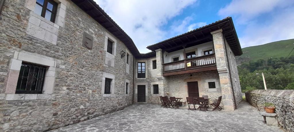 un grande edificio in pietra con sedie e un patio di Vivienda Vacacional La Perila a Rales