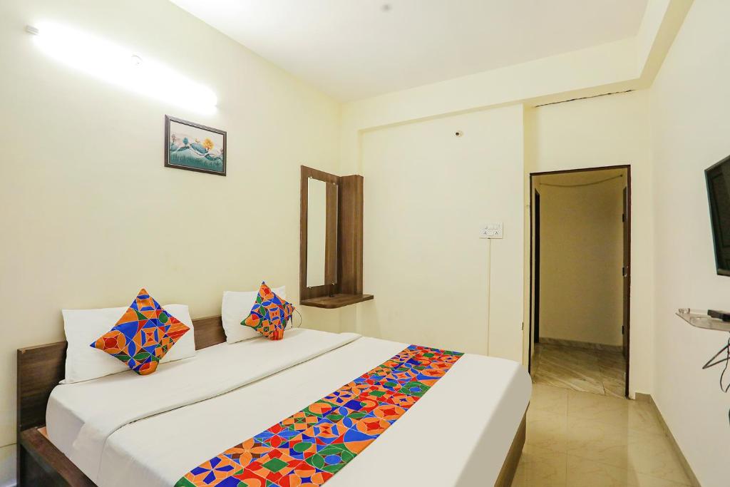 - une chambre avec un grand lit blanc et des oreillers colorés dans l'établissement FabHotel Seva Service Apartment, à Nagpur