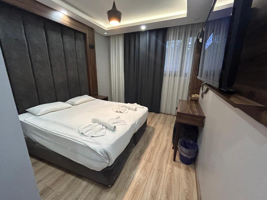 a bedroom with a bed with white sheets and a flat screen tv at Basilissis Hotel in Istanbul