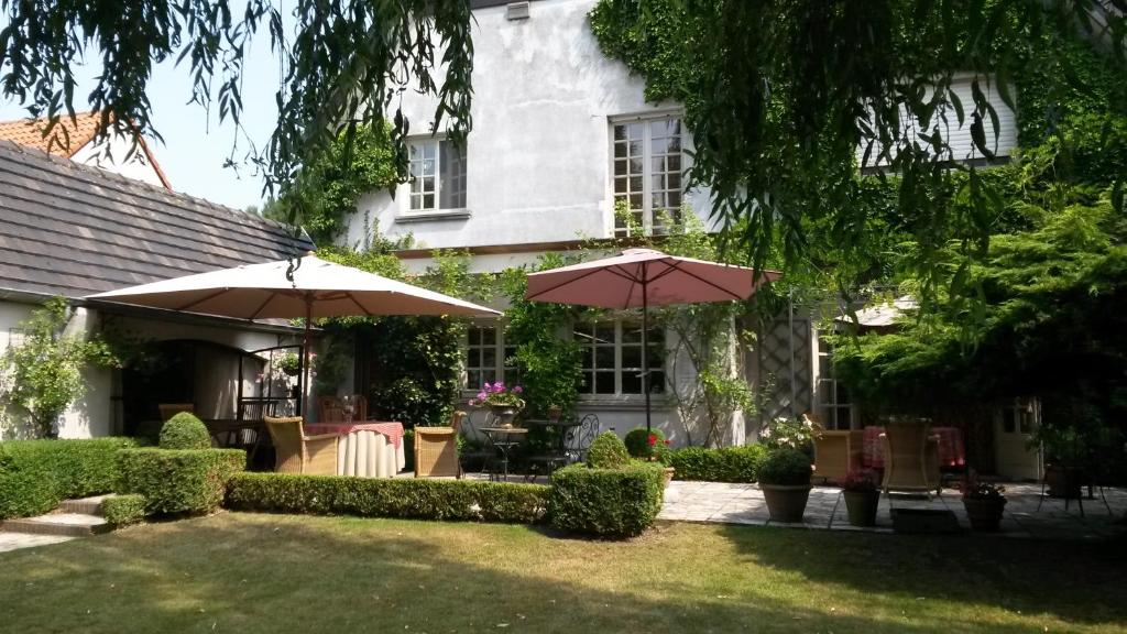 une maison avec deux parasols dans une cour dans l'établissement B&B Willow Lodge, à De Pinte