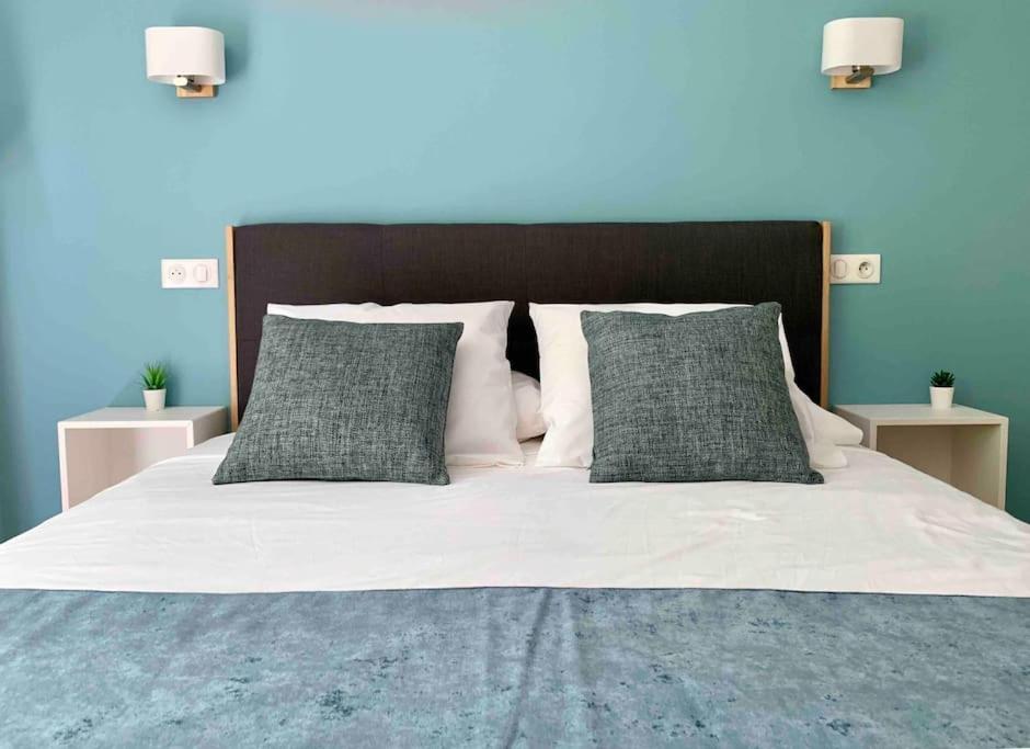 a bed with white sheets and gray pillows at Studio pour séjours d’affaires à La Défense in Courbevoie