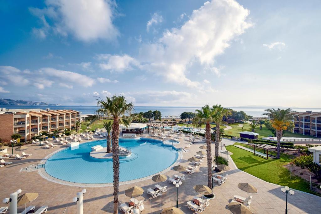 uma vista para a piscina num resort com palmeiras e cadeiras em TUI Magic Life Candia Maris - Adults Only em Amoudara Herakliou