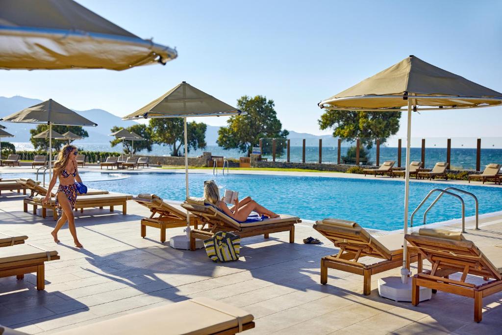 a woman walking by a pool at a resort at TUI Magic Life Candia Maris - Adults Only in Amoudara Herakliou