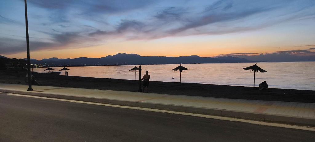 a group of people standing on a sidewalk near a body of water at Sun, Sea, and Sand-Only 20 Footsteps to the Beach in Korinthos