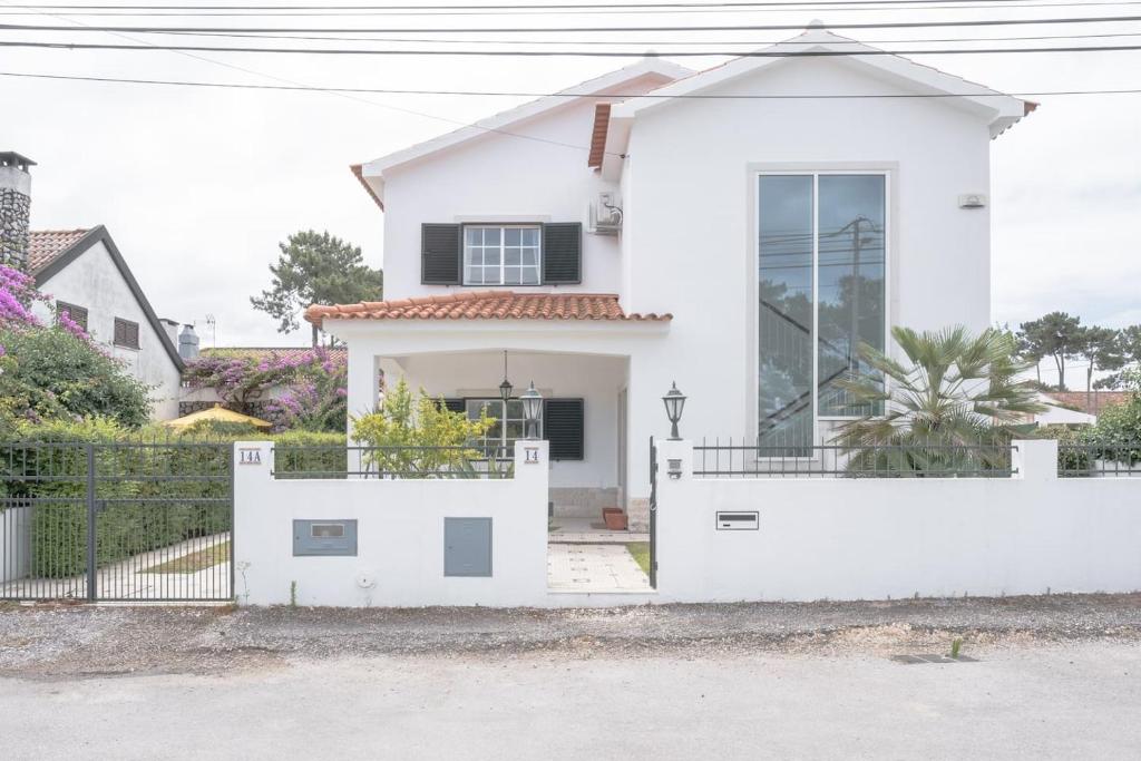 a white house with a white fence at Nini Beach House in Aroeira