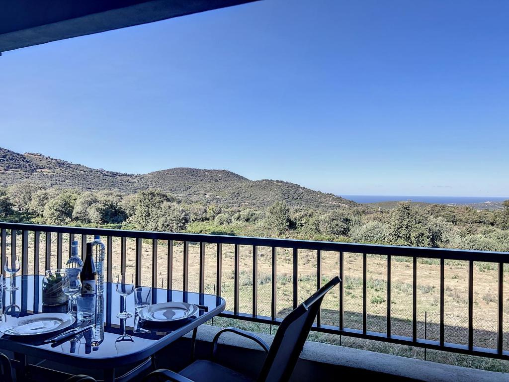 une table et des chaises sur un balcon avec vue sur l'océan dans l'établissement CALENZANA Appartement T3 avec vue mer !, à Calenzana