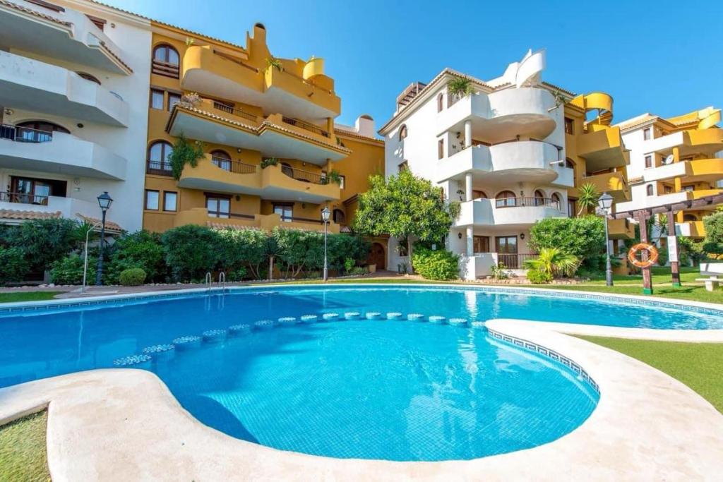 a swimming pool in front of a building at Apartamento La casa Verde in Punta Prima