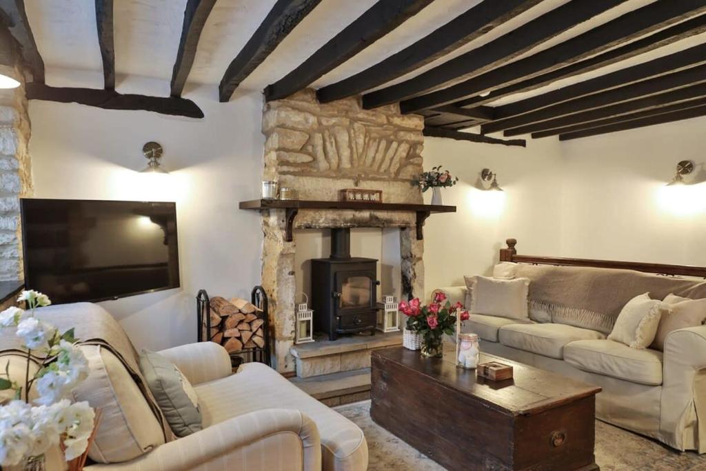 a living room with couches and a fireplace at Alexis Cottage Tetbury Cotswolds in Tetbury