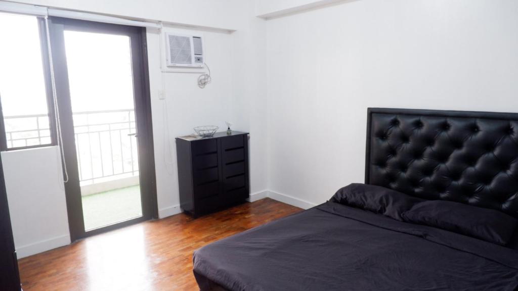 a bedroom with a black bed and a black dresser at 2BR near BGC & Makati. Karaoke, Netflix, Amazon Prime in Manila
