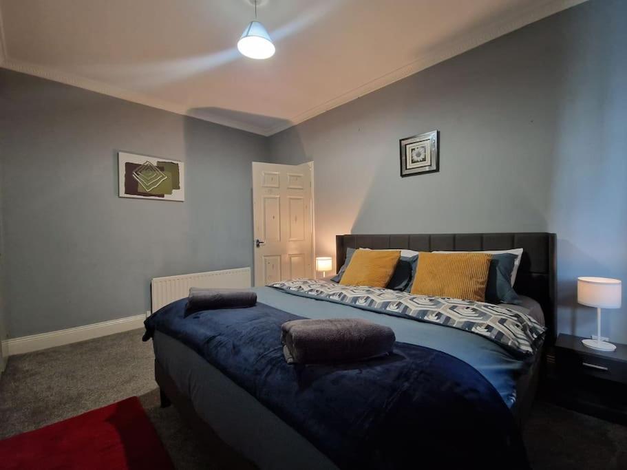 a bedroom with a bed with blue sheets and yellow pillows at Primos Place - 2 Bedroom in Ashington in Ashington