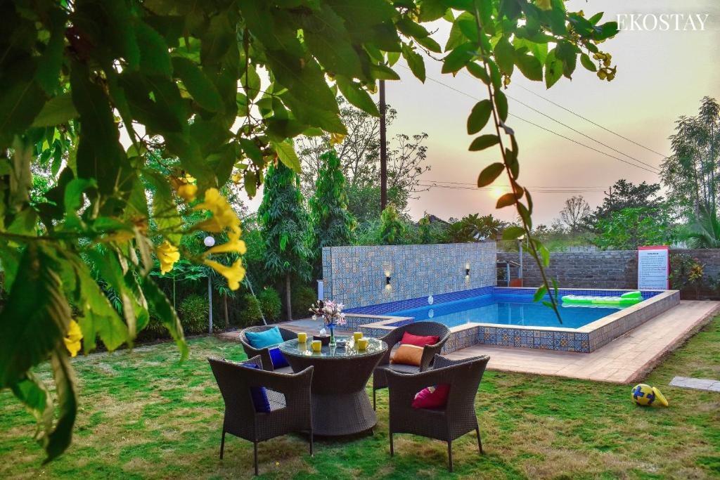 a garden with a table and chairs and a pool at EKOSTAY- Nest Villa in Karjat