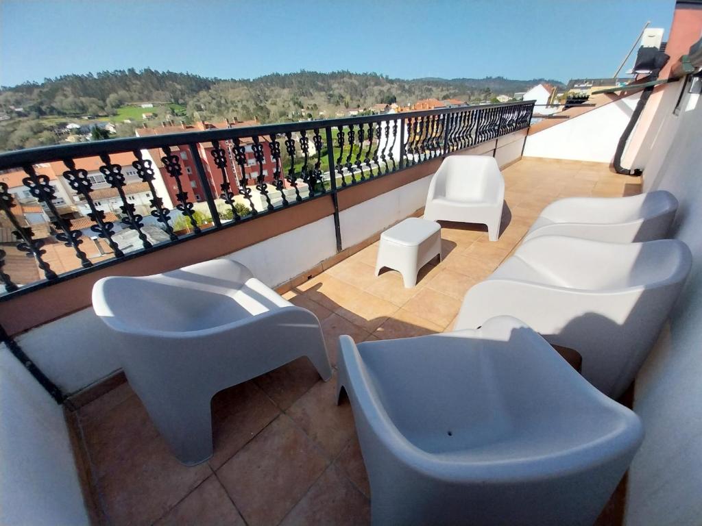 a balcony with white tables and white chairs at La Parada del Camino in Negreira