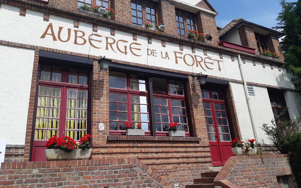 a building with red doors and flowers in the window at Logis hôtel & Restaurant - Auberge de la Forêt in Hazebrouck