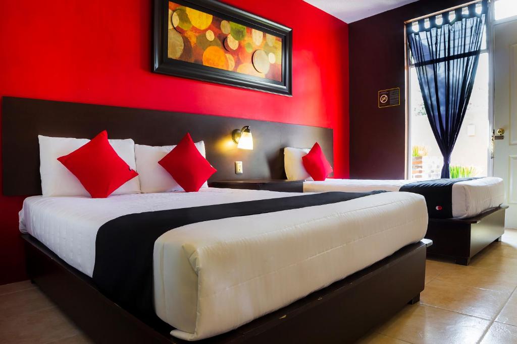 a bedroom with two beds and a red wall at Hotel Del Valle, Tecamachalco in Tecamachalco