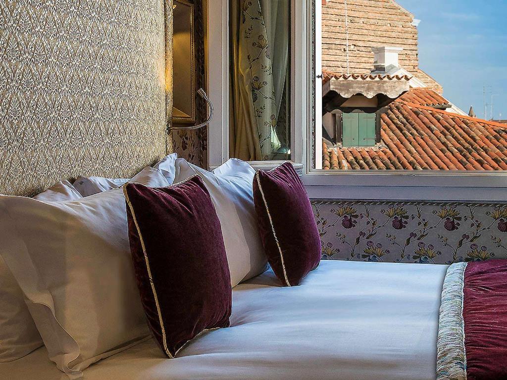 a bed with pillows sitting in front of a window at Papadopoli Hotel Venezia - MGallery Collection in Venice