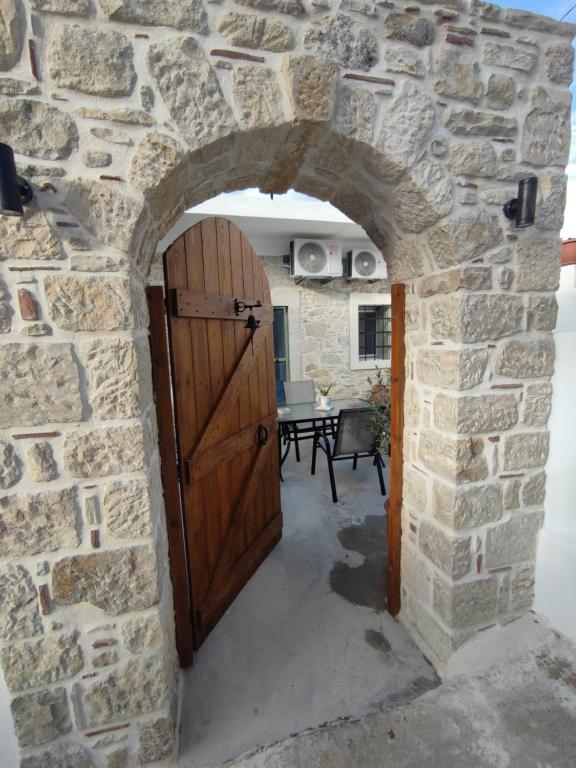 um arco numa parede de pedra com uma porta de madeira em La maison d Aspasia em Kamilárion