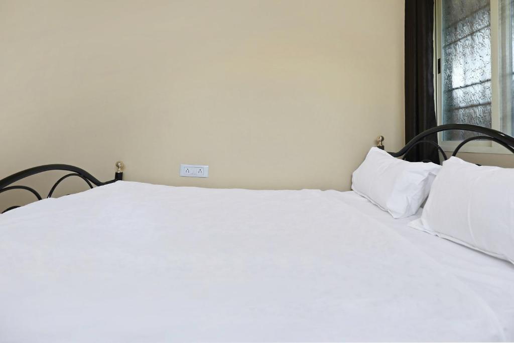 two white beds in a room with a window at SPOT ON Krishnaa Comforts Near Cubbon Park in Bangalore