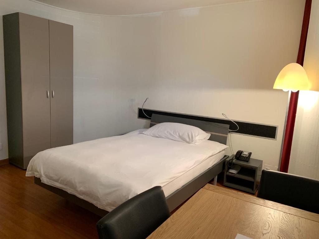 ein Schlafzimmer mit einem Bett, einem Stuhl und einer Lampe in der Unterkunft Congress Apartments by Hotel du Commerce in Basel