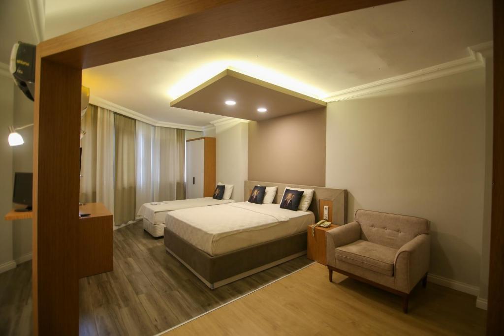 a bedroom with two beds and a couch and a chair at ÇEVİK PALACE HOTEL in Antalya