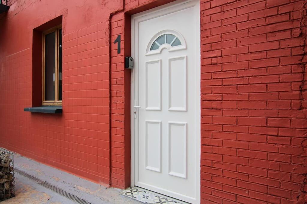 een witte deur aan de zijkant van een rood bakstenen gebouw bij La brique Rouge, 5P Parking in Noeux-les-Mines