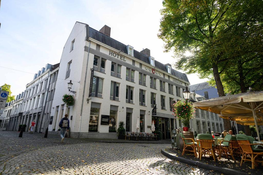 a white building with tables and chairs on a street at Derlon Hotel Maastricht in Maastricht