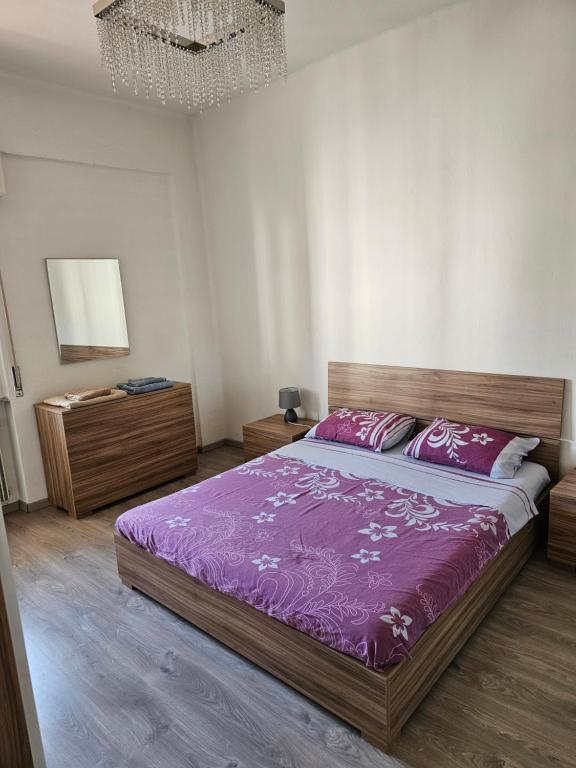 Un dormitorio con una cama con sábanas moradas y una lámpara de araña. en Appartamento vicino università, en Piacenza
