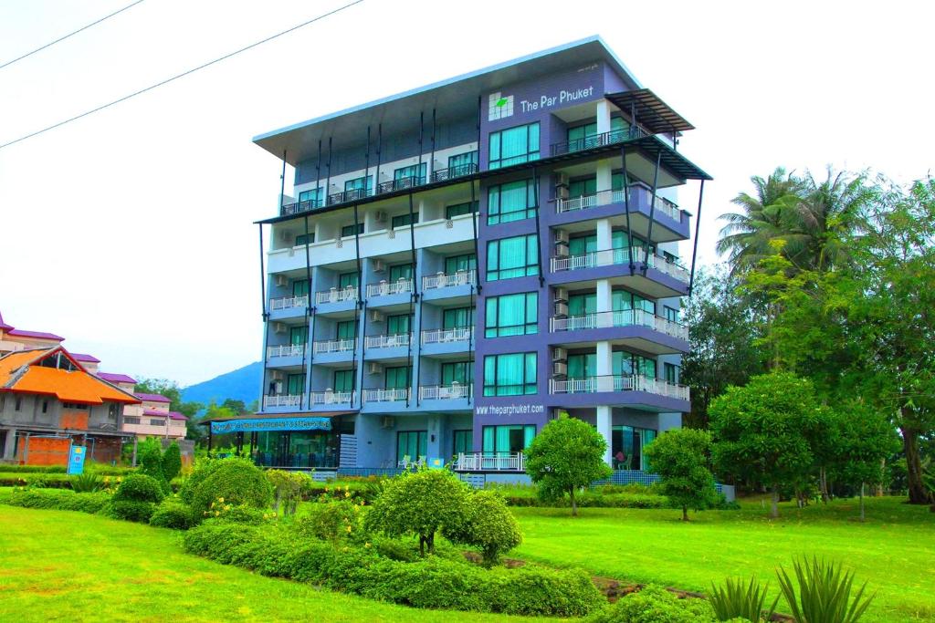 a tall blue building with a green yard at The Par Phuket SHA Plus in Kathu