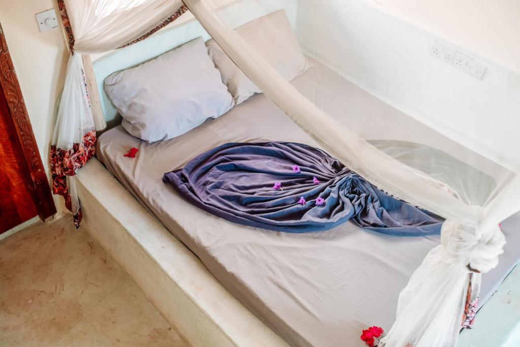 an unmade bed with a purple blanket on it at Marvelous Zanzibar in Jambiani