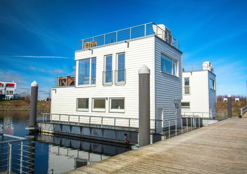 a white house on a dock on the water at Schwimmendes Haus - An Bord Zwei in Kappeln