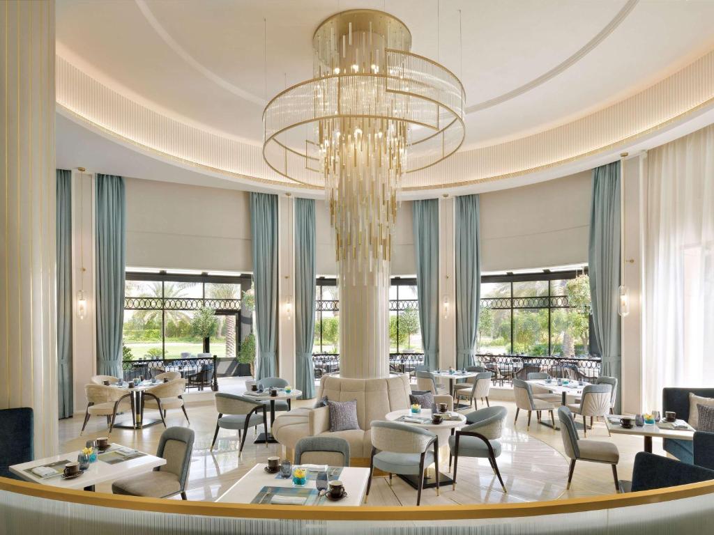 a restaurant with tables and chairs and a chandelier at Mövenpick Hotel Bahrain in Manama