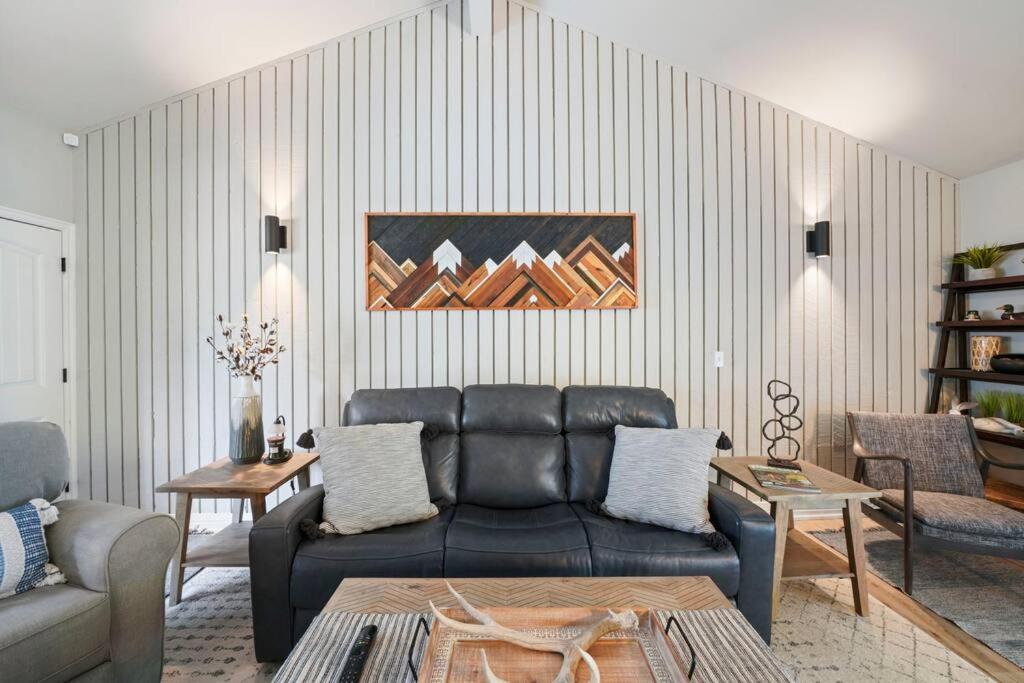 een woonkamer met een zwarte leren bank en een tafel bij Cozy Bungalow in Provo for 4 Guests in Provo