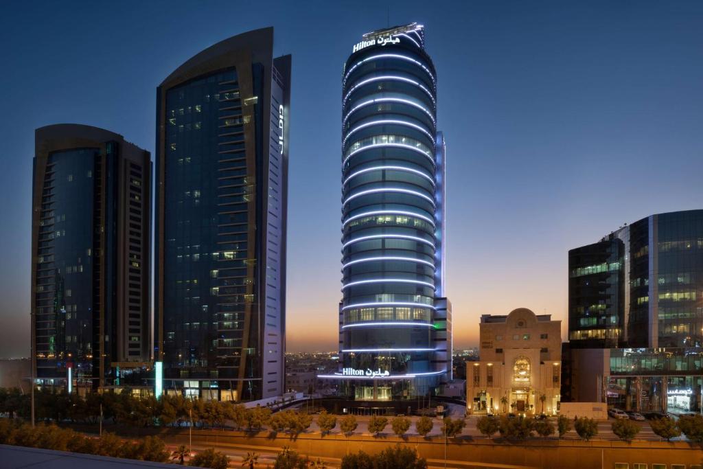een hoog gebouw in een stad 's nachts bij Hilton Riyadh Olaya in Riyad
