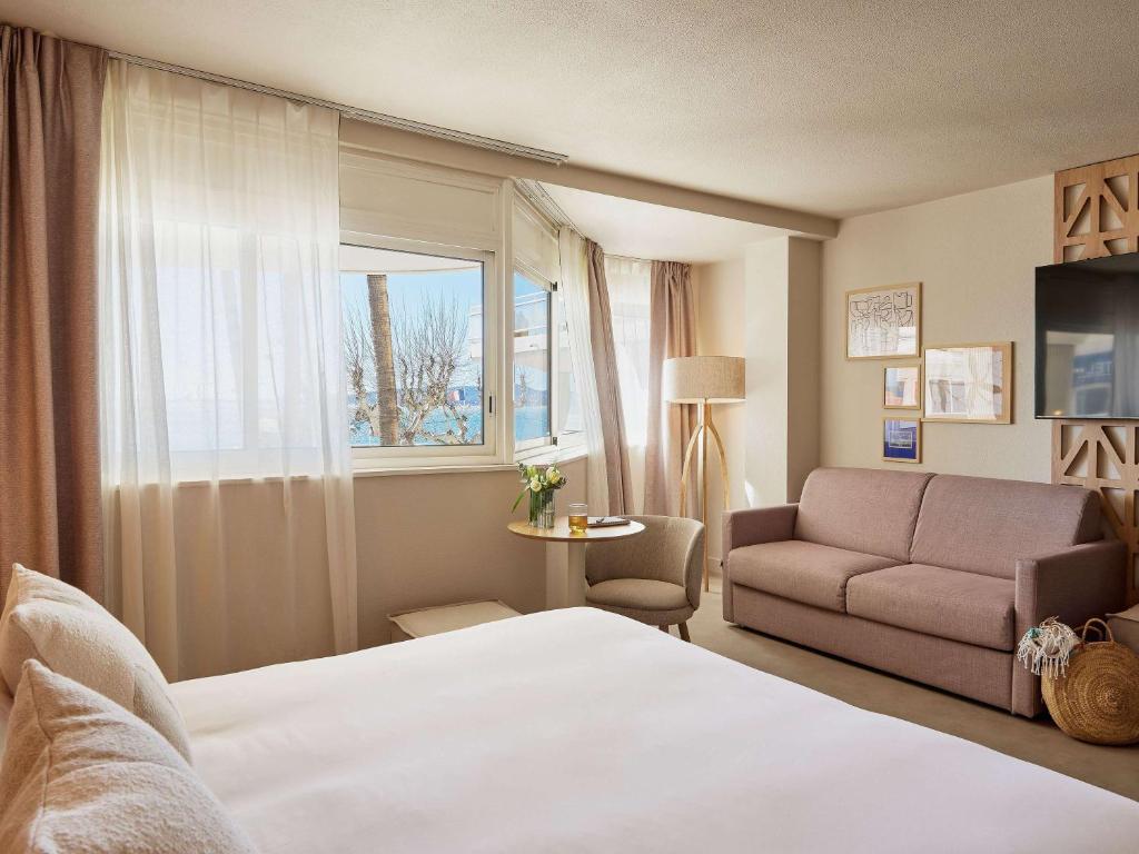 une chambre d'hôtel avec un lit et un canapé dans l'établissement Mercure Saint Raphael Centre Plage, à Saint-Raphaël