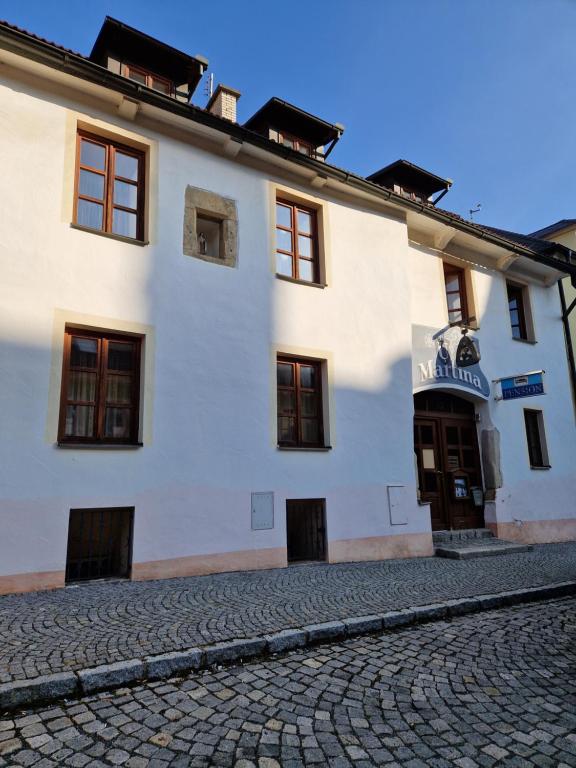 a white building on a cobblestone street at Pension U Martina in Domažlice