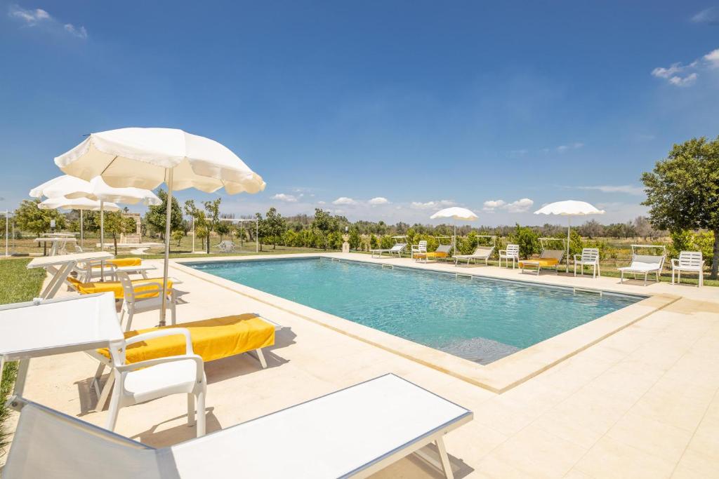 einen Pool mit Stühlen und Sonnenschirmen in einem Resort in der Unterkunft Tenuta Melissa in Aradeo